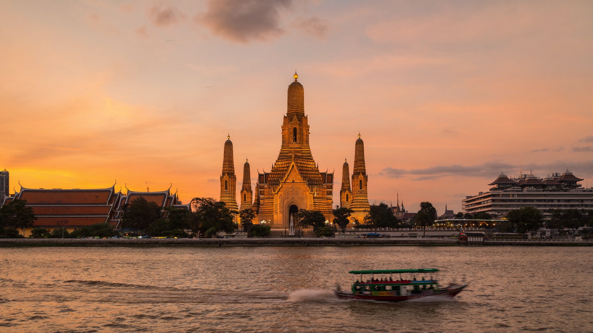 Wat Arun i Bangkok i solnedgang med longtail-båt