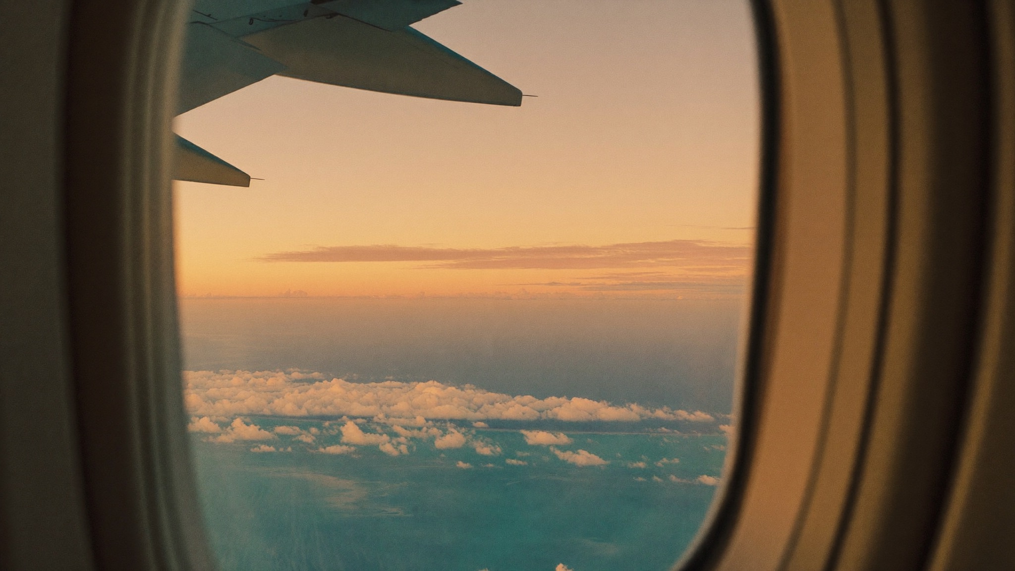 Utsikt over flyvingen i solnedgang over turkist hav